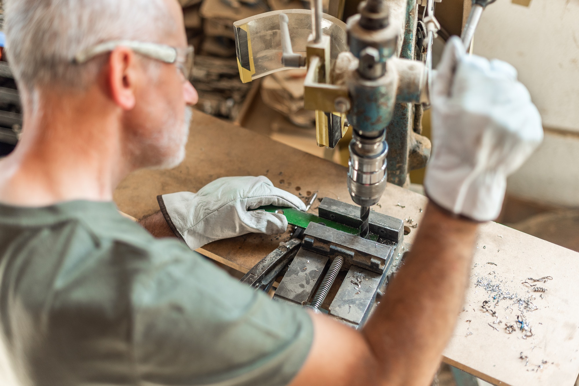 Adult person drilling metal with safety gloves